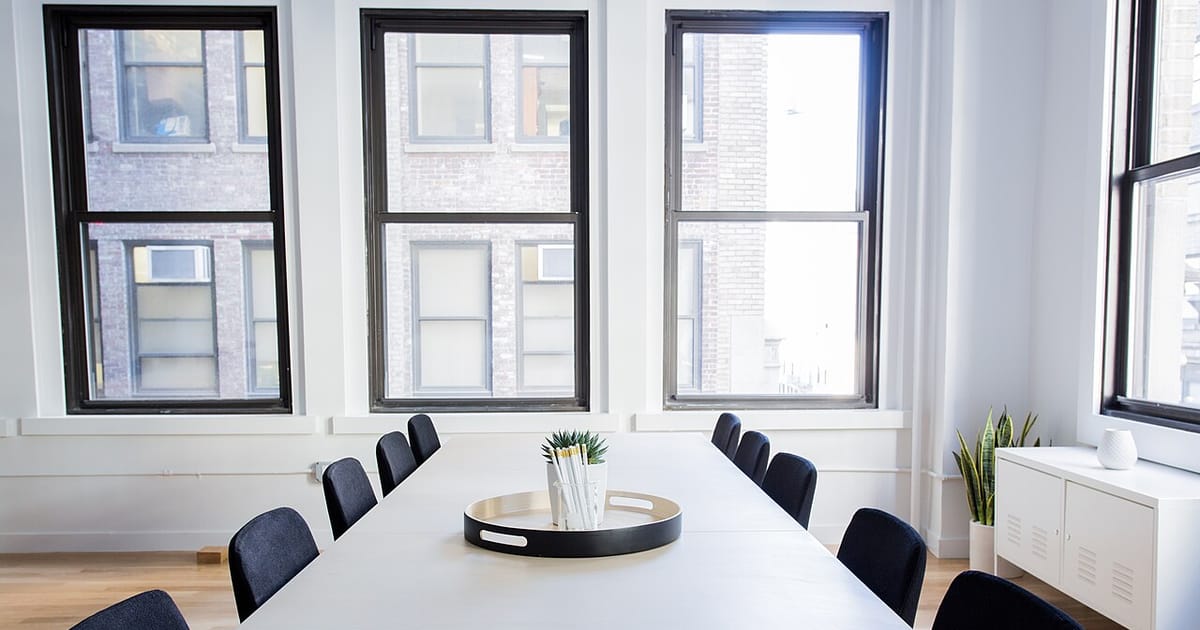 A minimalist white meeting room with a conference table and chairs
